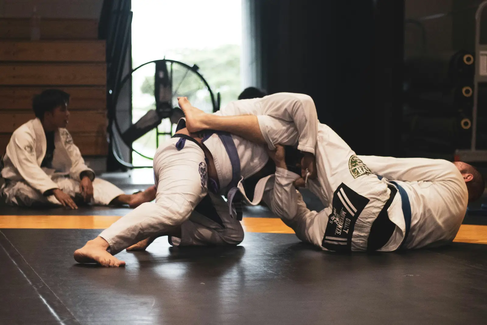 Two BJJ athletes in gi rolling on the mat
