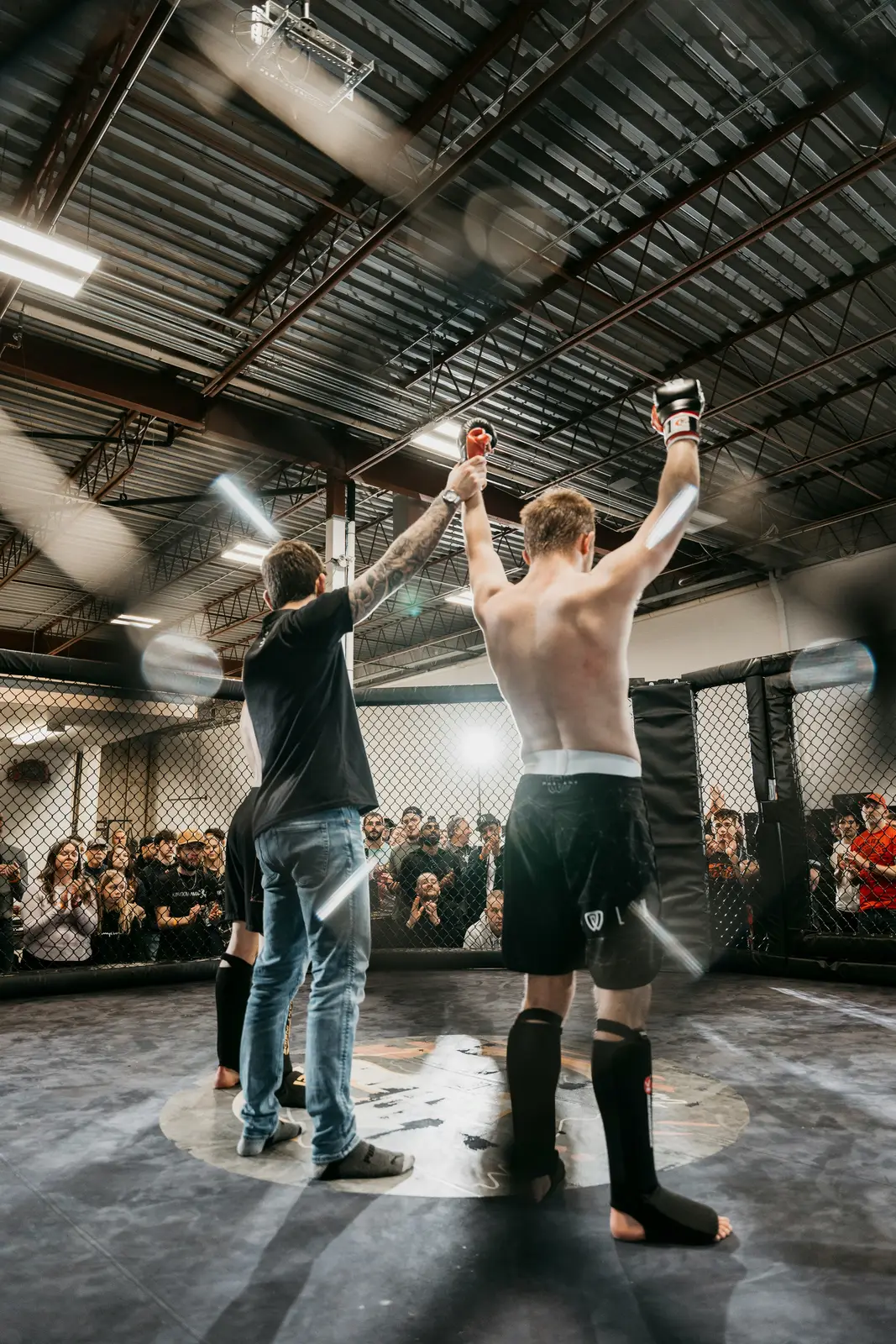 Referee raising the winner's arm in the cage