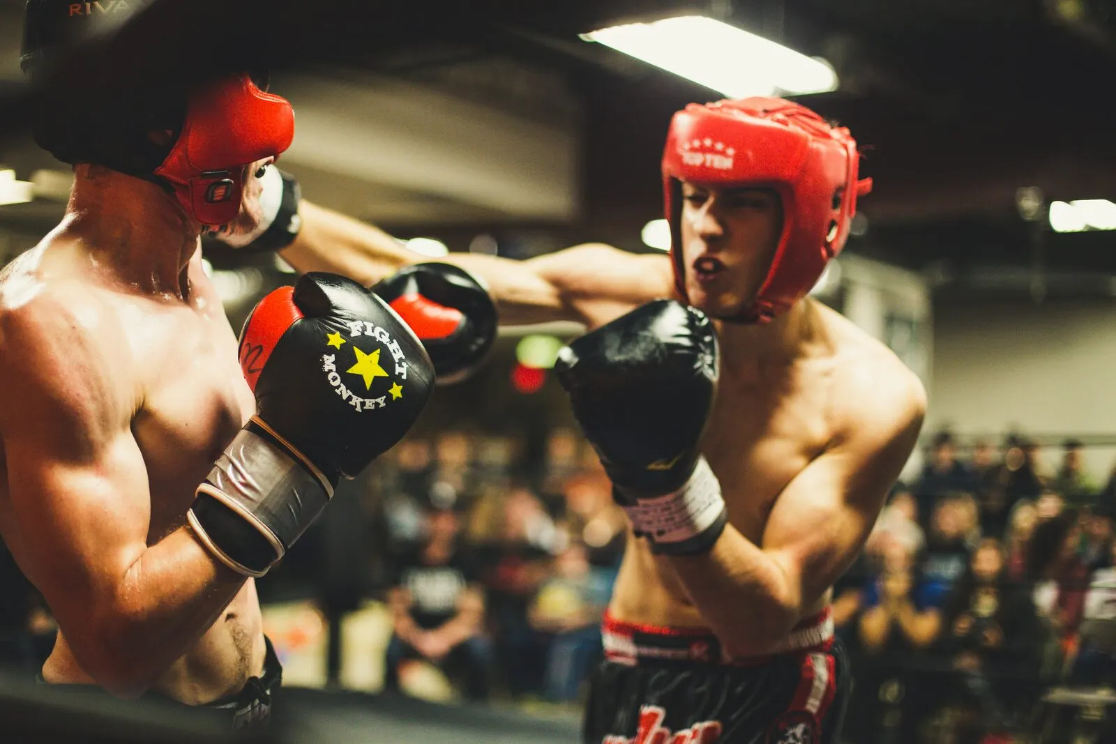 Two kickboxers in headgear exchanging punches in the ring