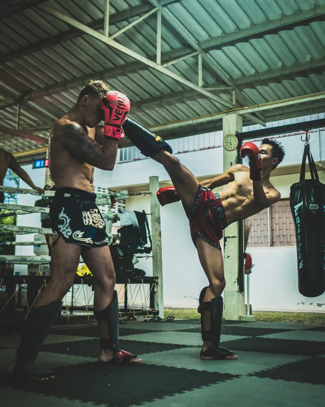 Muay Thai fighter throwing a high kick at a camp