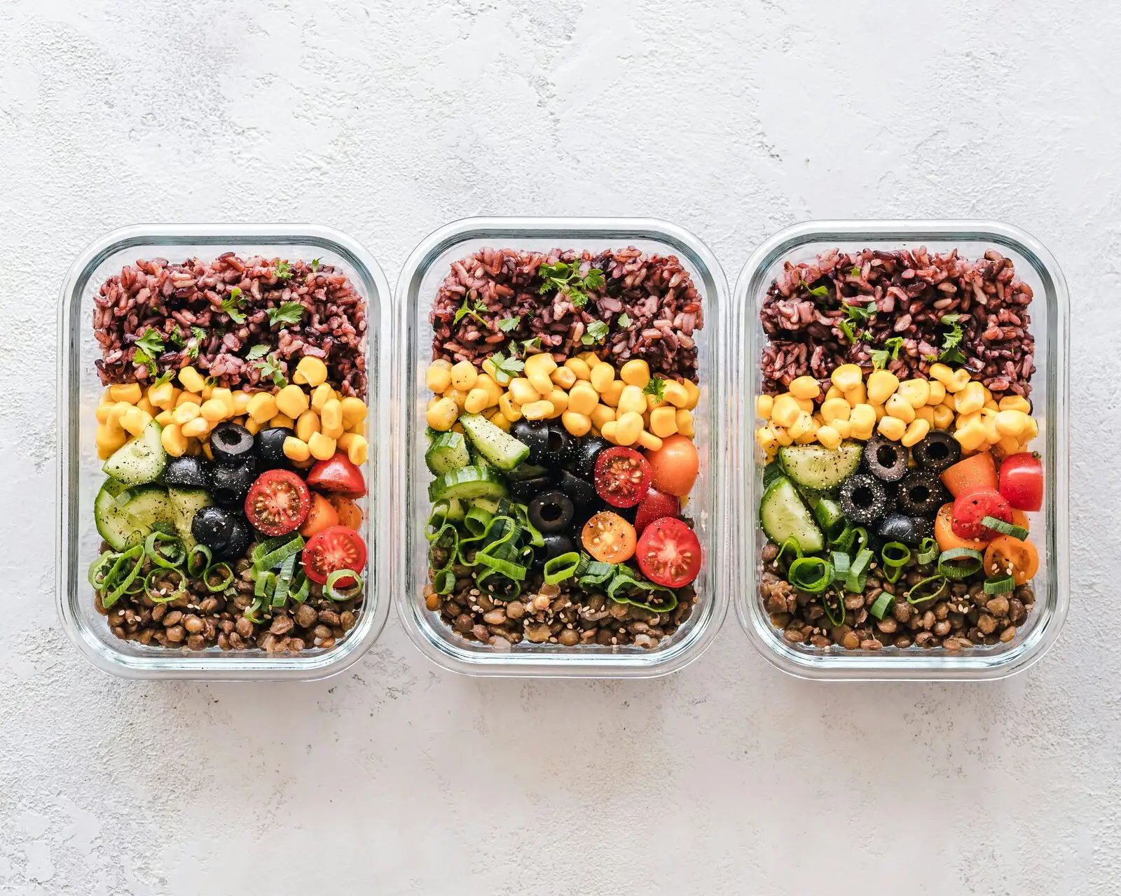 Three meal-prep boxes with rice, beans and vegetables